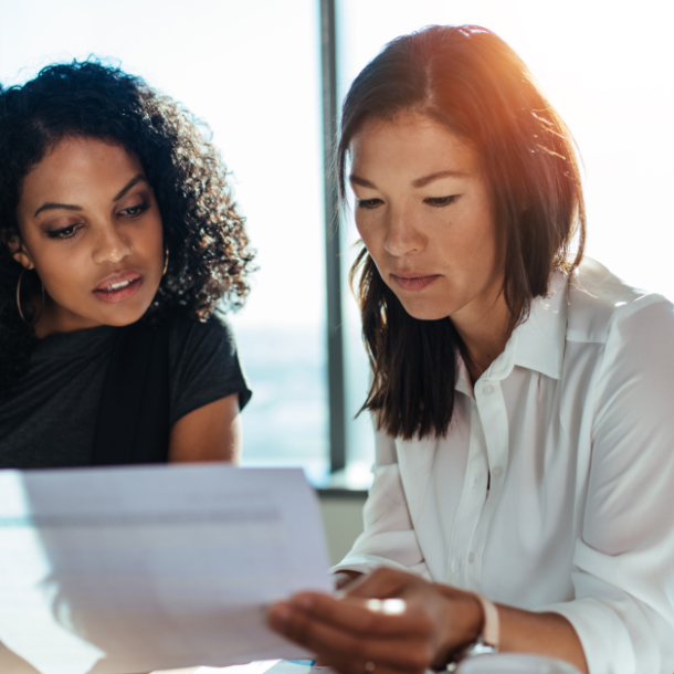 Two women comparing at financial wellness benefits in an office. Payactiv blog post image.