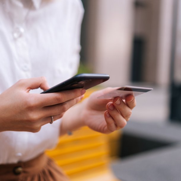 A woman holding phone pays for something with her credit card.