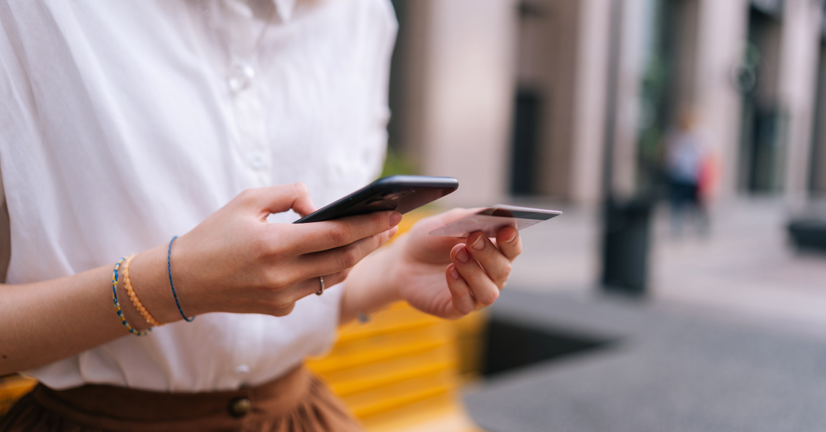 A woman holding phone pays for something with her credit card.