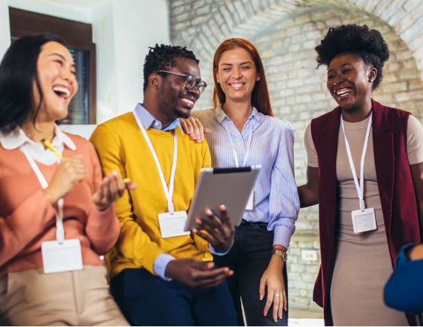 Workers wearing name tags stand in a circle laughing