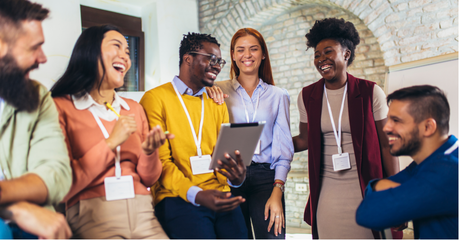 Workers wearing name tags stand in a circle laughing