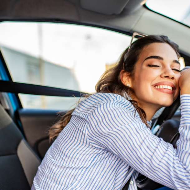 Girl smiling while holding steering wheel in her car.