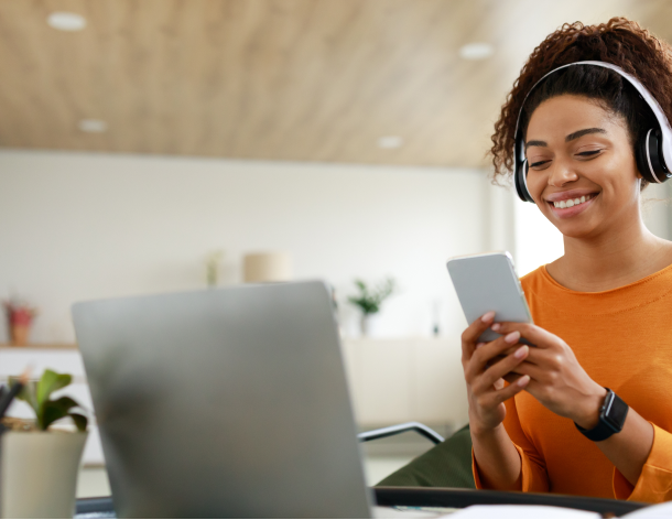 A woman wearing headphones sitting at a computer pays herself first thing on payday.