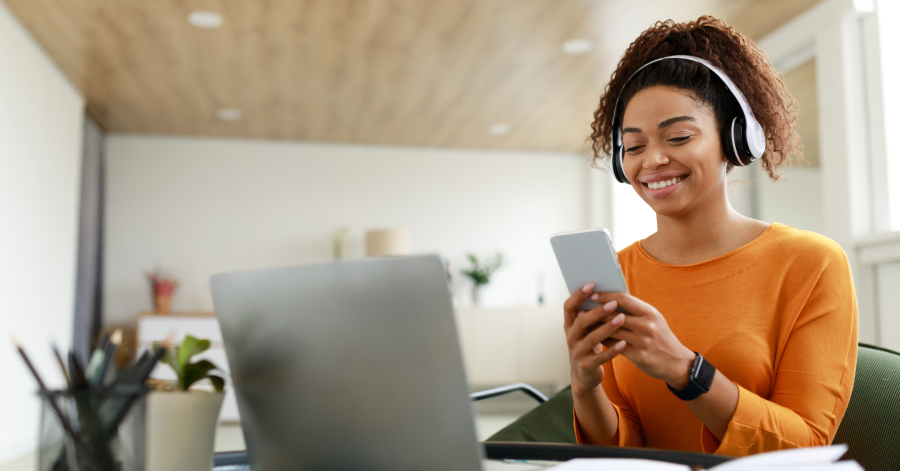 A woman wearing headphones sitting at a computer pays herself first thing on payday.