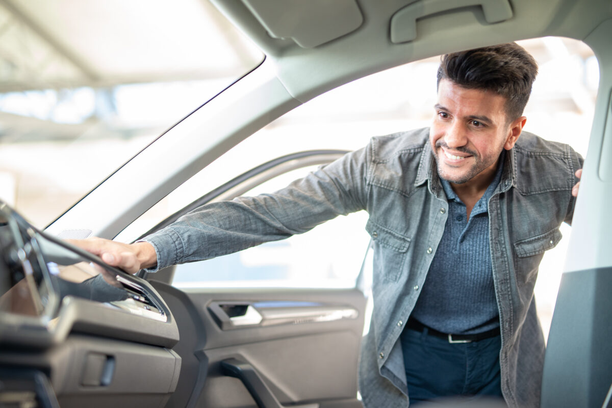 young man at a car dealership, inspecting new car.