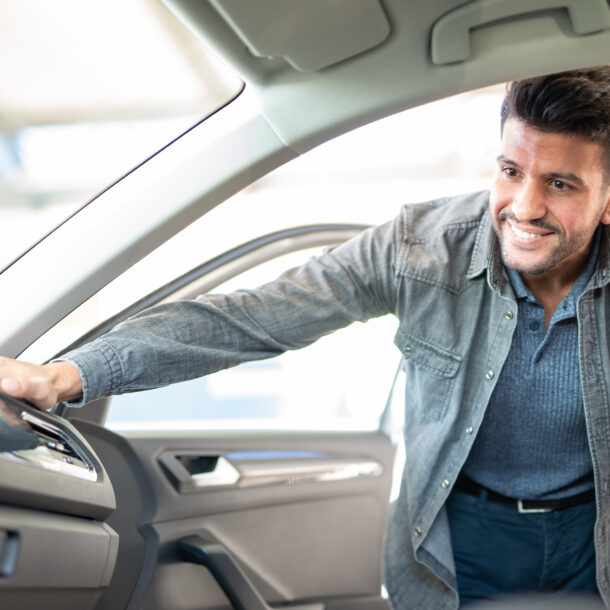 young man at a car dealership, inspecting new car.