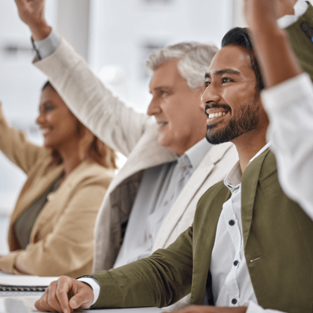 5 employees sitting at a table. 3 are raising their hands.