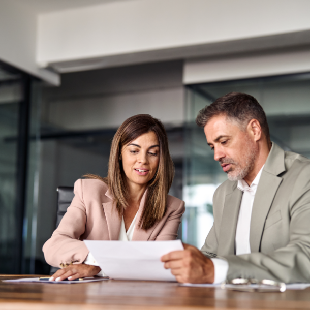An employee and human resource manager are looking at paperwork, together.