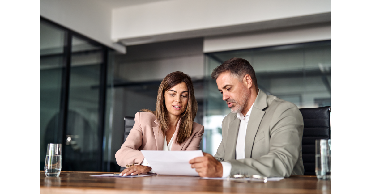 An employee and human resource manager are looking at paperwork, together.