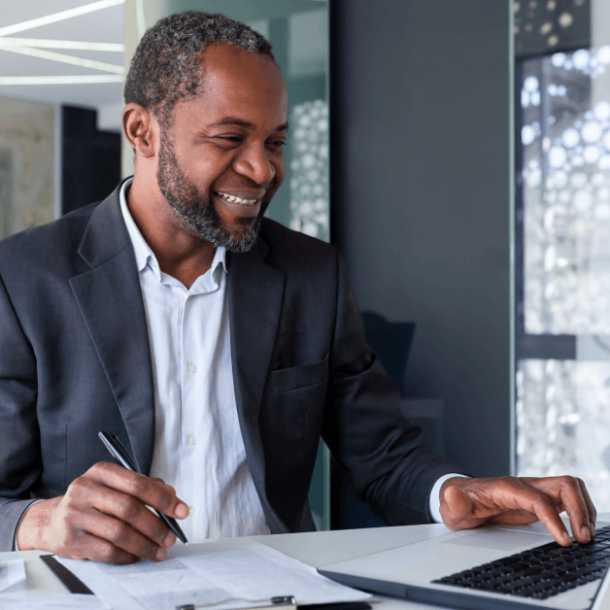 A man is smiling while working at his desk.