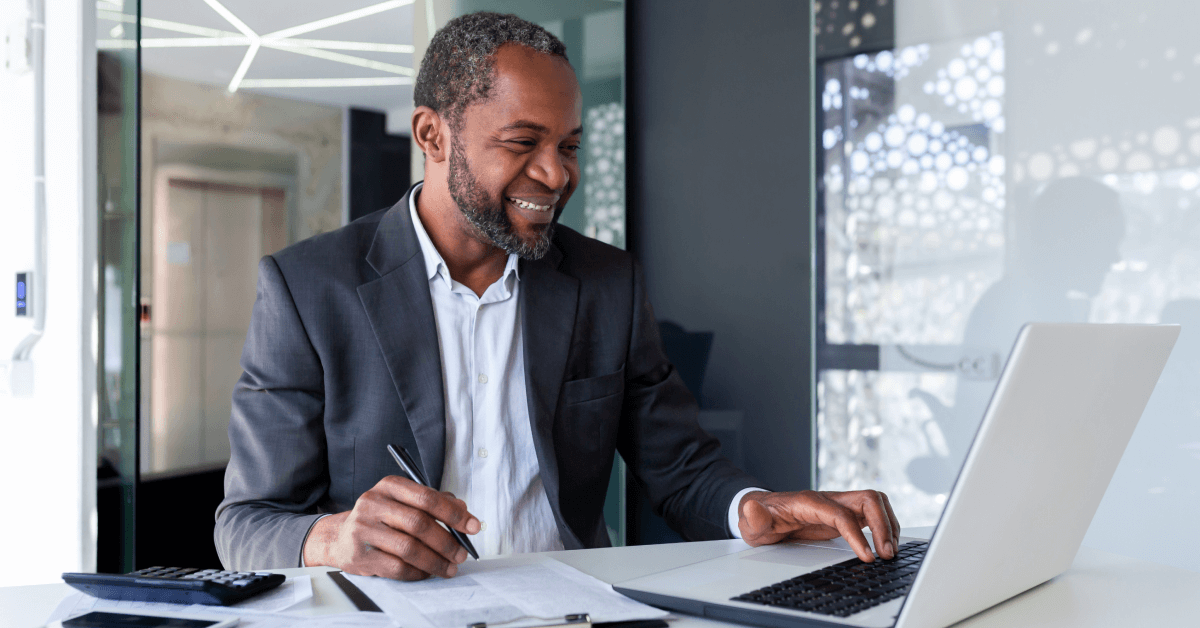 A man is smiling while working at his desk.