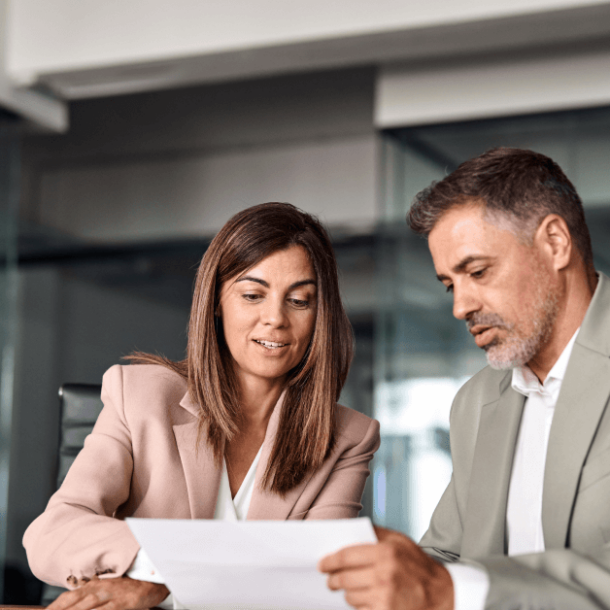 Two professional executives discussing financial accounting papers working together in office.