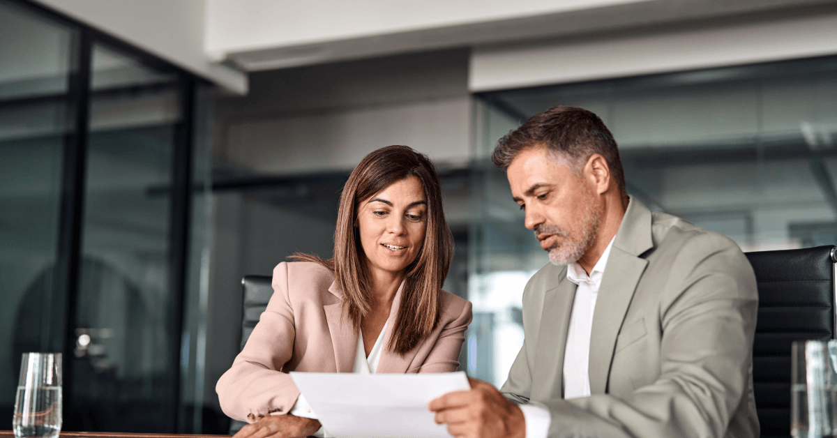 Two professional executives discussing financial accounting papers working together in office.