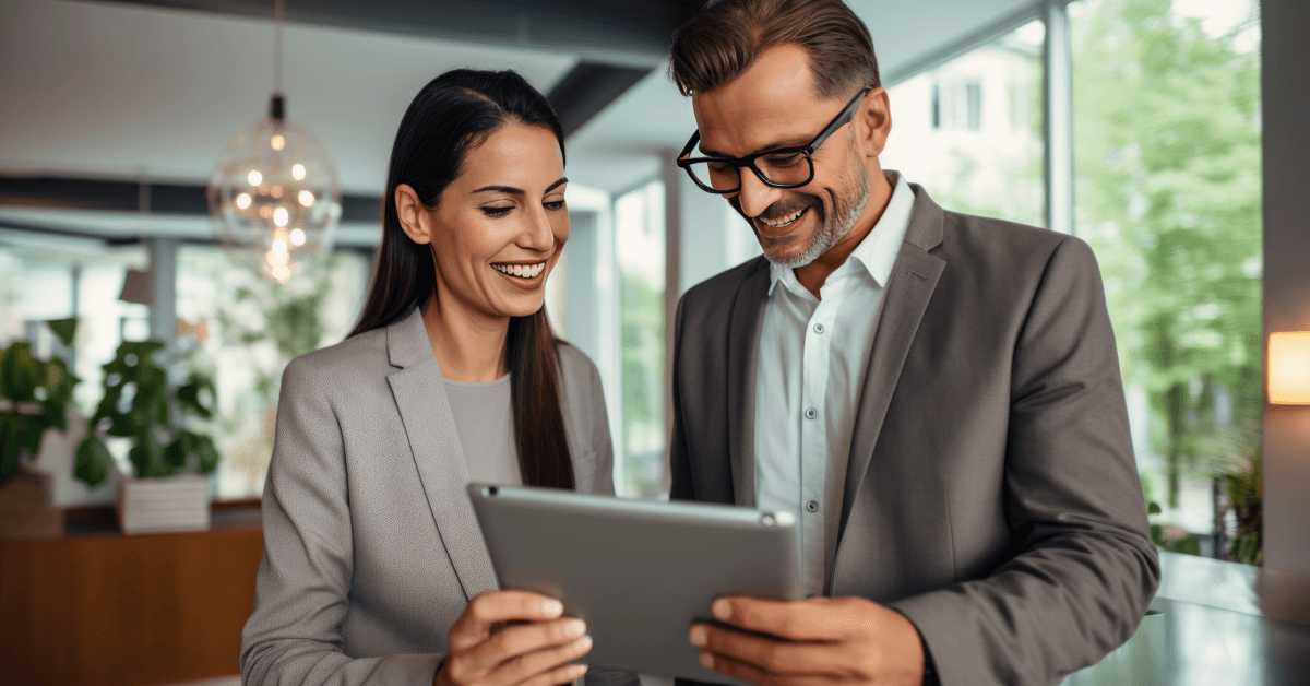two happy employees looking at a tablet.