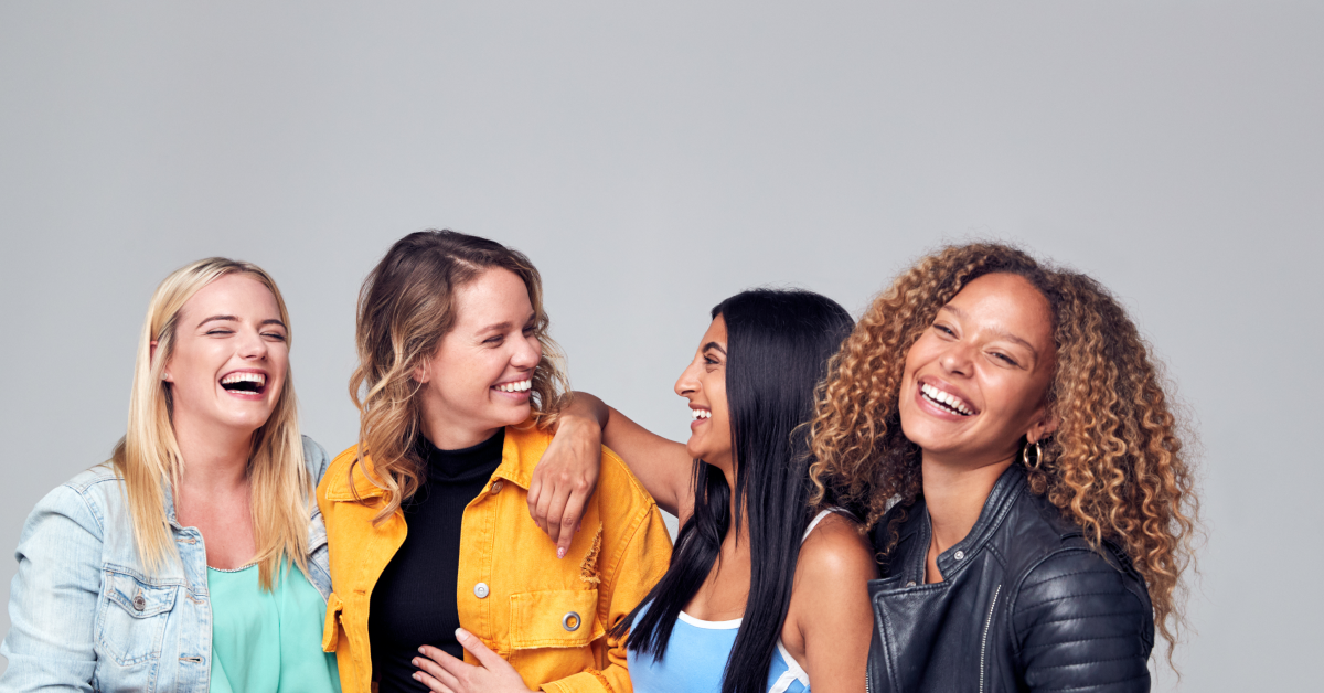 Group Studio Portrait Of Multi-Cultural Female Friends Smiling Into Camera Together