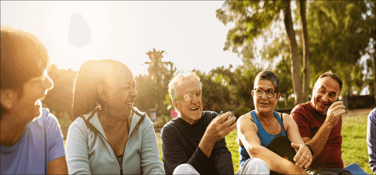 Happy multiracial senior friends drinking a tea after workout activities in a park
